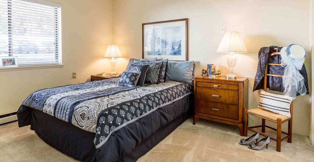 A cozy bedroom with a neatly made bed, nightstands, and warm lighting.