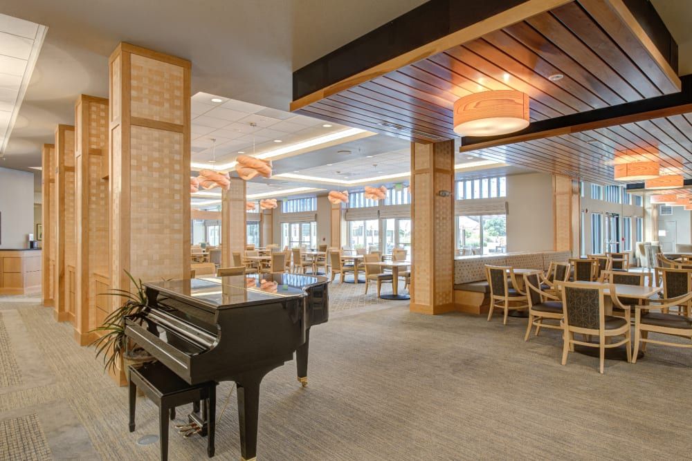 A modern restaurant interior featuring a grand piano and elegant seating areas.