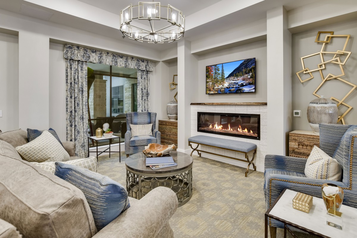 A modern living room featuring a sleek fireplace, comfortable seating, and a stylish chandelier.