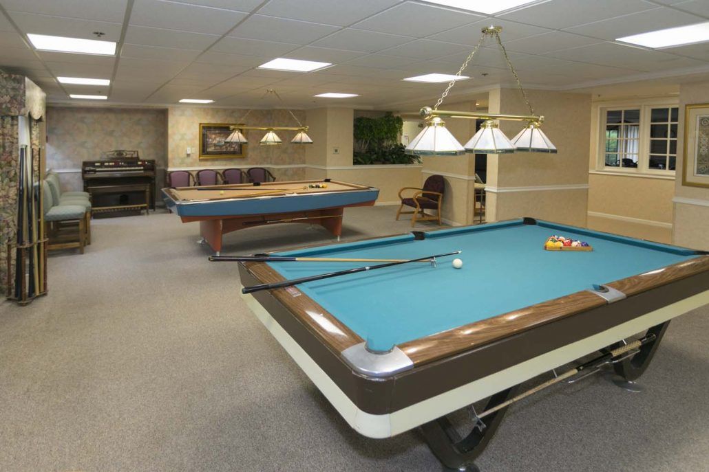 A game room featuring multiple pool tables and comfortable seating.