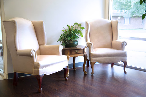 A cozy seating area featuring two elegant chairs and a lush plant.
