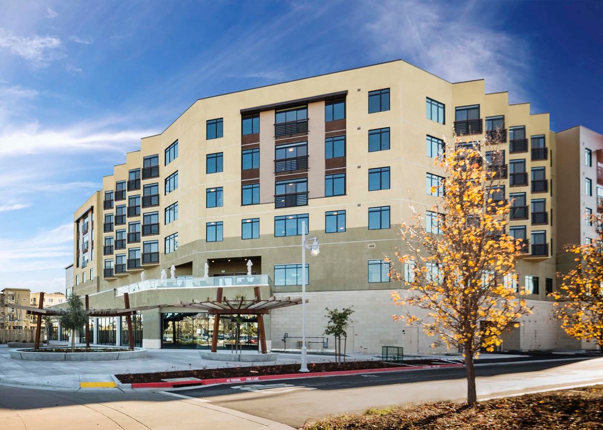 A modern hotel building with a sleek design, set against a clear blue sky.