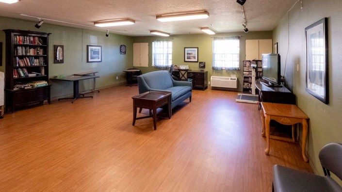 A spacious room with a sofa and table, featuring hardwood floors and decorative elements.