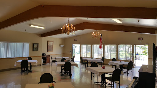 A spacious dining area with tables and chairs, illuminated by chandeliers, providing a welcoming atmosphere.