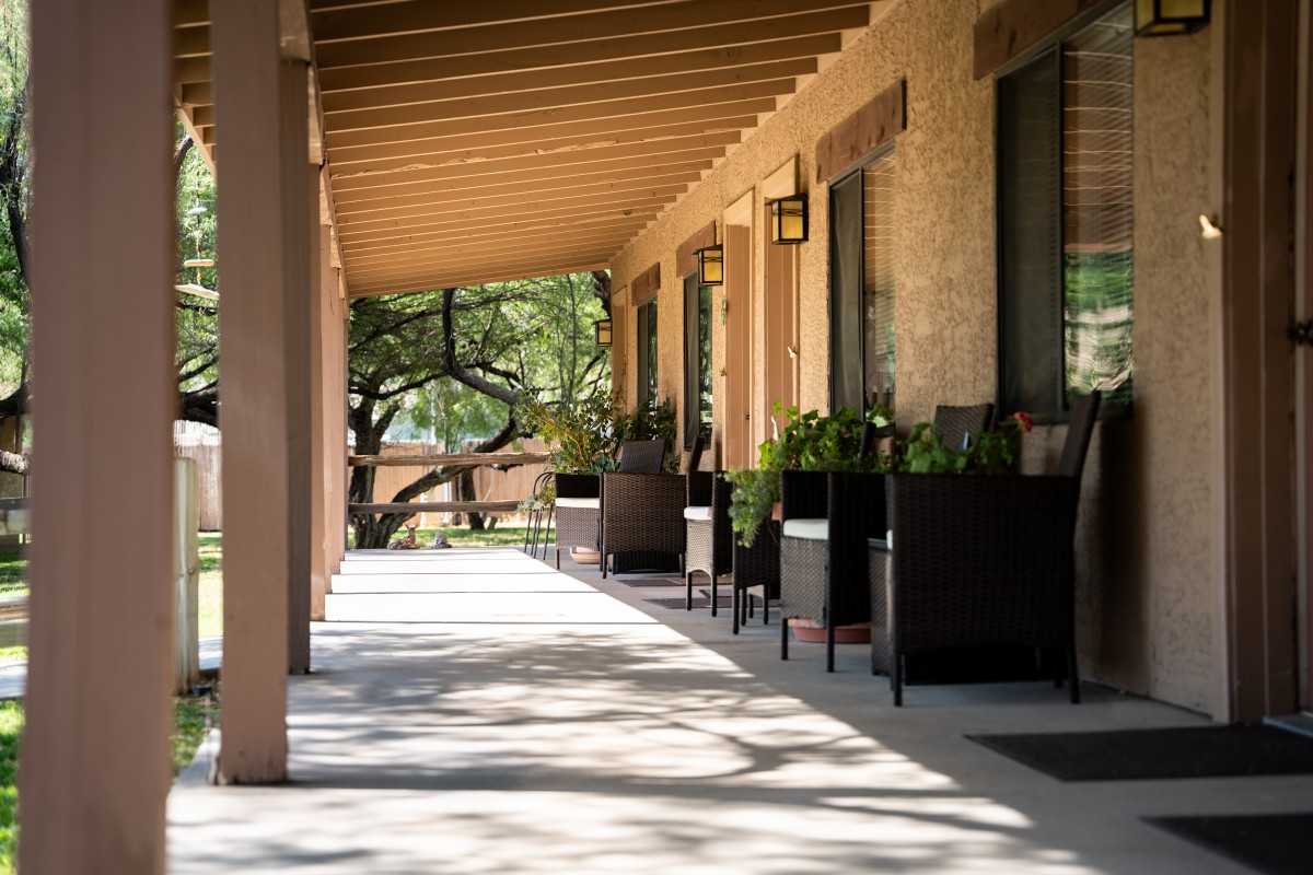 A quiet, shaded porch with outdoor seating and potted plants.