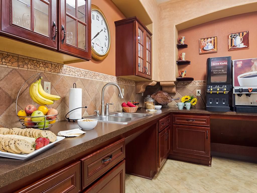 A cozy kitchen with wooden cabinets, a sink, and a variety of fruits on the countertop.