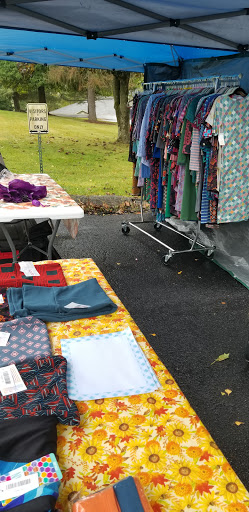 A vibrant market scene featuring tables of colorful fabrics and clothing hanging on a rack.