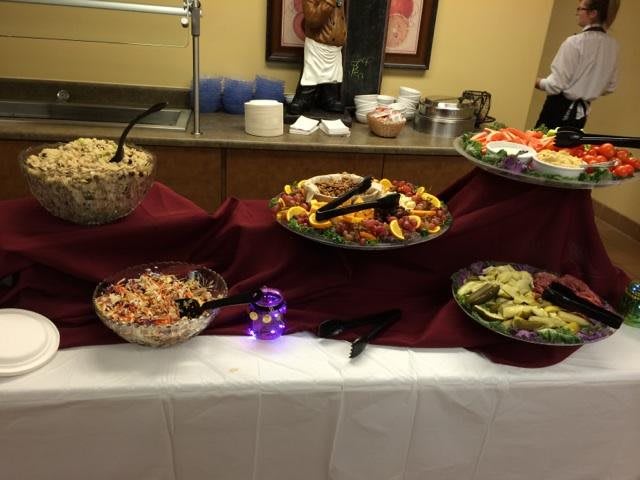 A buffet table featuring a variety of salads and vegetables, elegantly arranged with serving utensils.