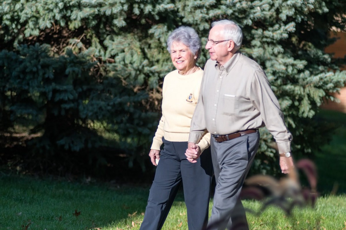 An elderly couple enjoying a walk outdoors on a sunny day.