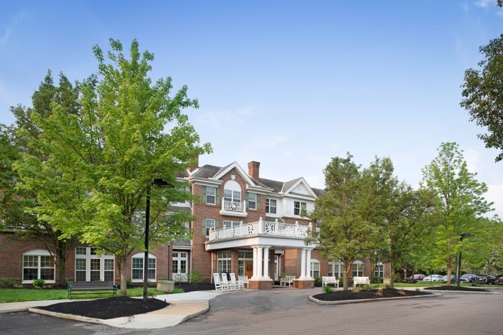 A two-story brick building surrounded by trees under a clear blue sky.