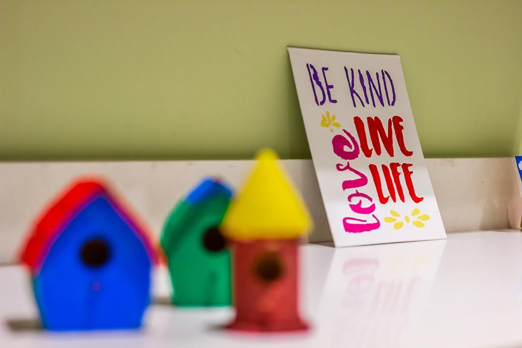 A motivational sign with colorful birdhouses in the foreground.