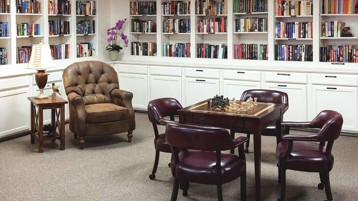 A cozy study room with a chessboard and bookshelves.