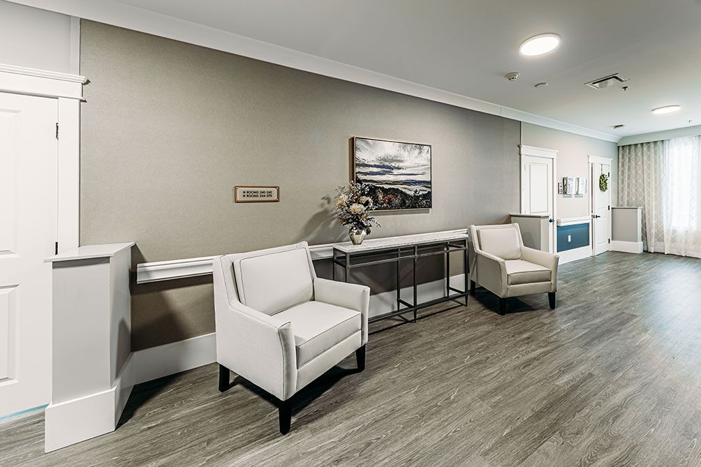 A modern waiting area with two armchairs and decorative elements, including a painting and flowers on a side table.