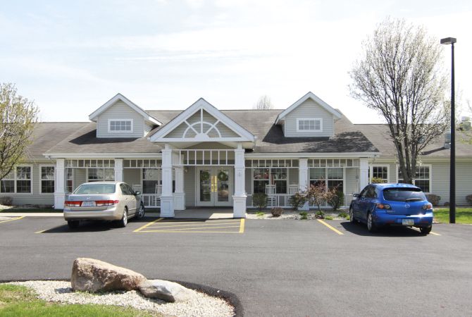 A small building with a front porch and parking area.