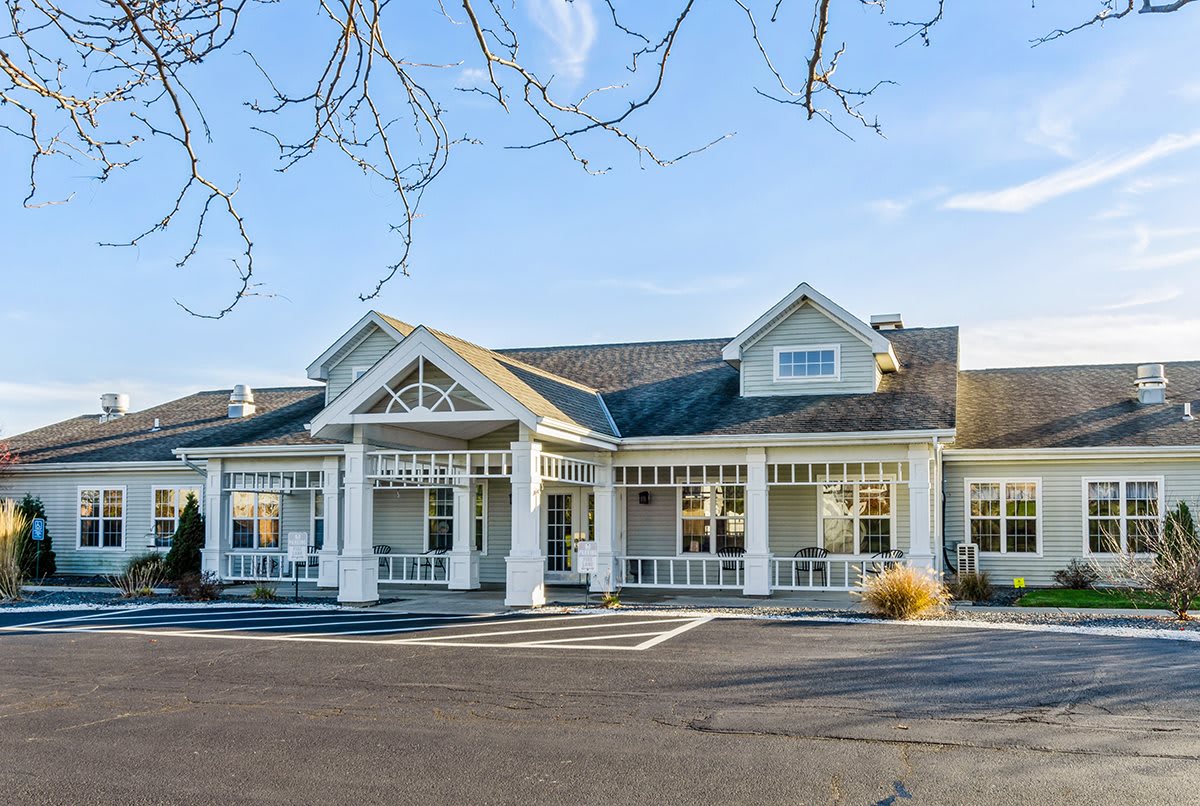 A large, white residential building with a spacious front porch and peaked roof.