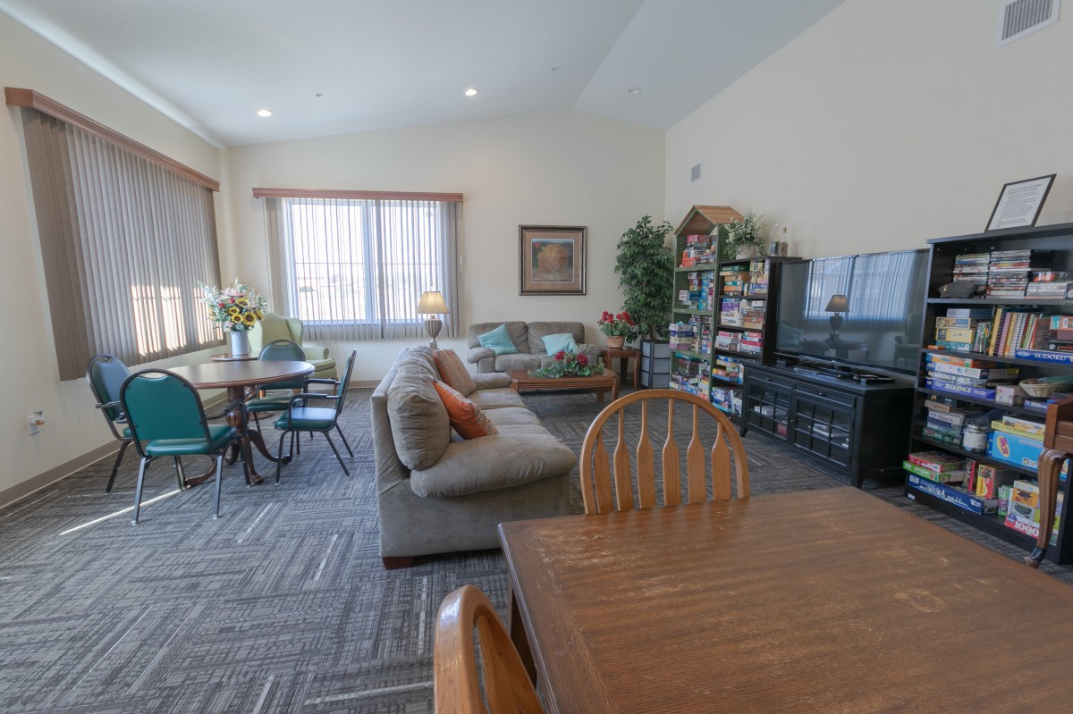 A cozy living room featuring a comfortable couch, a large television, and a dining area with a wooden table and chairs.