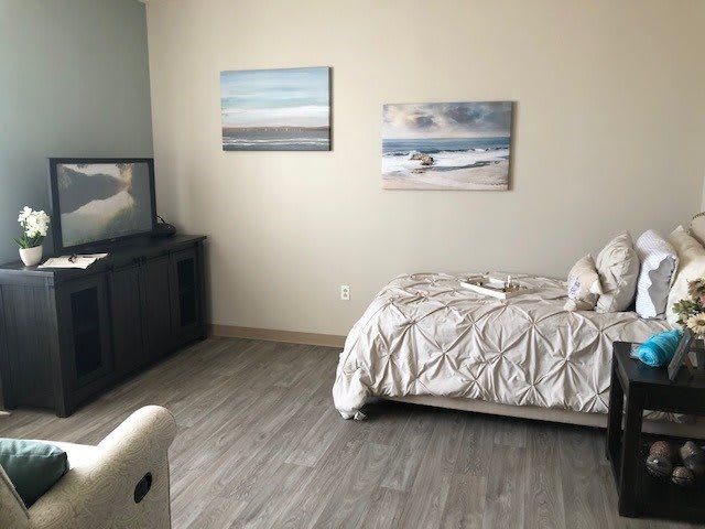 A minimalist bedroom with a single bed, TV, and wall art.