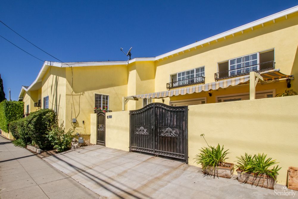 A yellow residential house with a gated entrance on a sunny day.