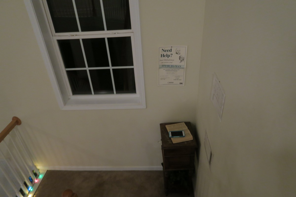 An indoor corner with a window, a sign about recycling, and a waste bin.