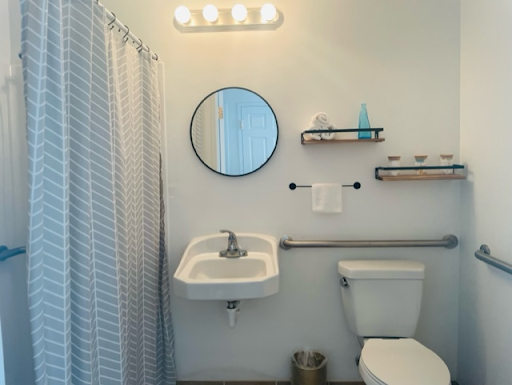 A modern and clean bathroom featuring a round mirror, sink, and neatly arranged shelves.