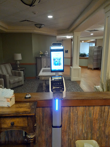A modern kiosk displaying a digital screen in a healthcare facility's reception area.