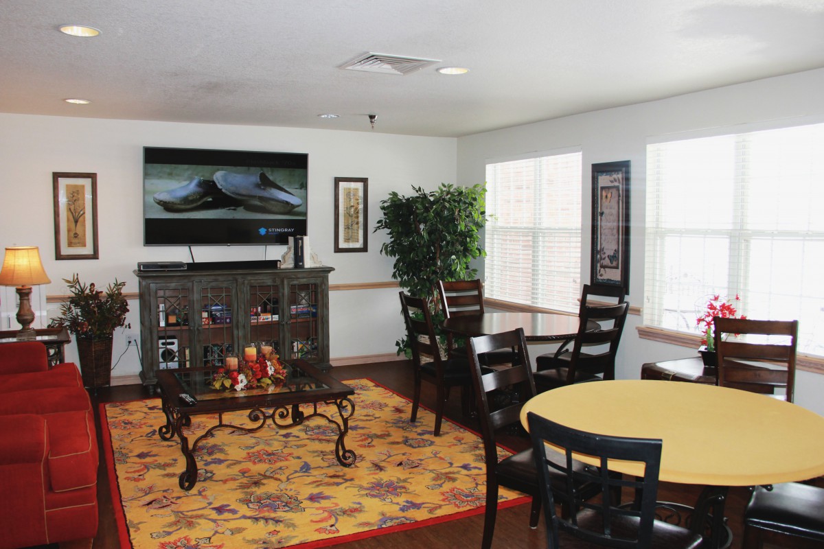 A cozy living room with a television, chairs, and decorated table.