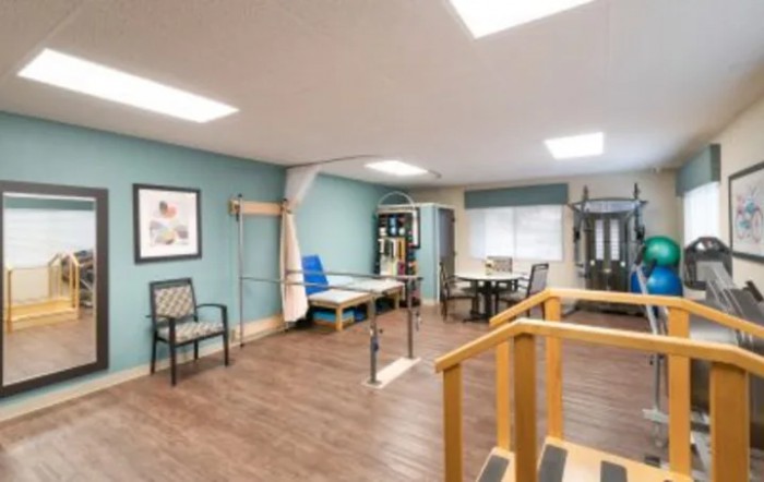 A well-lit rehabilitation room equipped with various physical therapy tools and furniture.