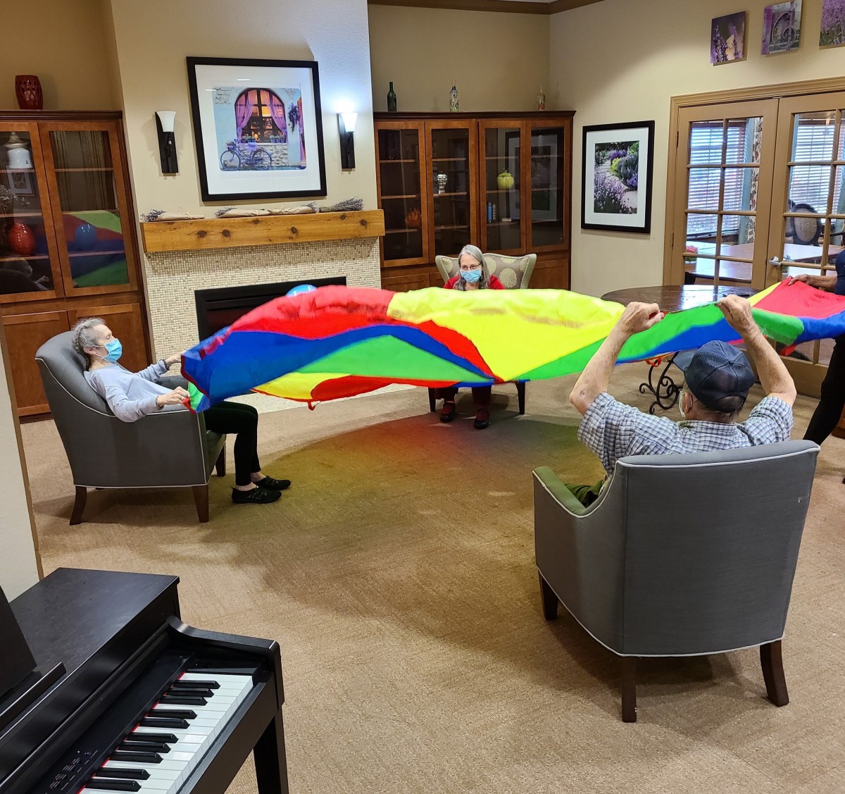 A group of senior citizens engaging in a colorful parachute activity indoors.