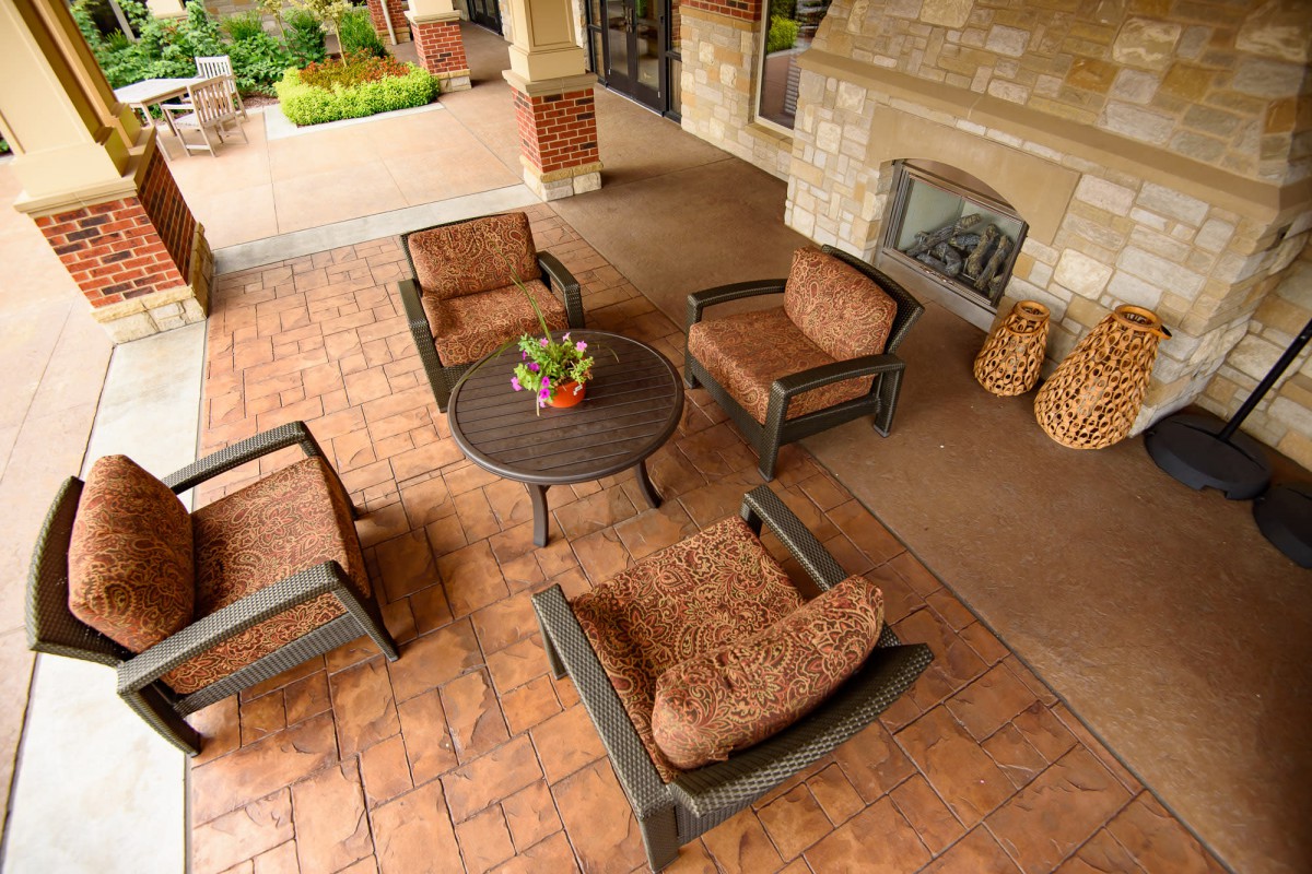 Outdoor seating area with chairs and a table on brick flooring, featuring a fireplace.