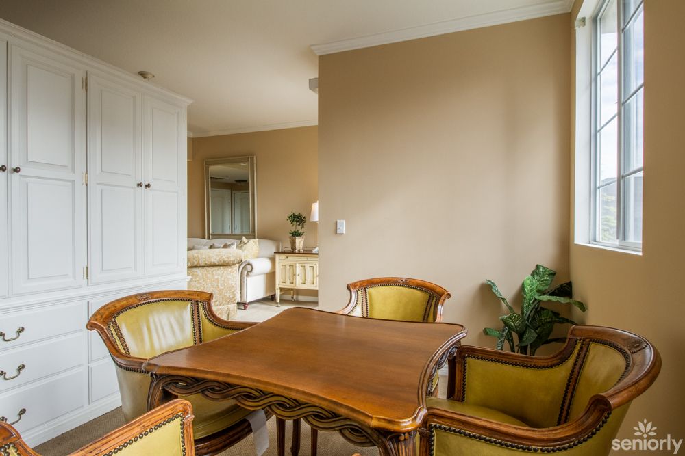 A cozy dining area with a wooden table and chairs, surrounded by neutral tones and greenery.