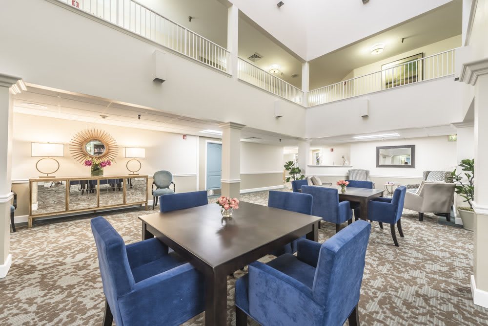 A modern dining area with blue upholstered chairs surrounding a dark wood table, set in an open and well-lit interior space.
