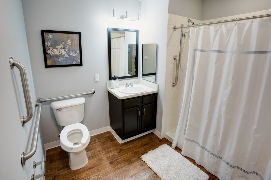 A modern and clean bathroom with a toilet, sink, mirror, and shower.