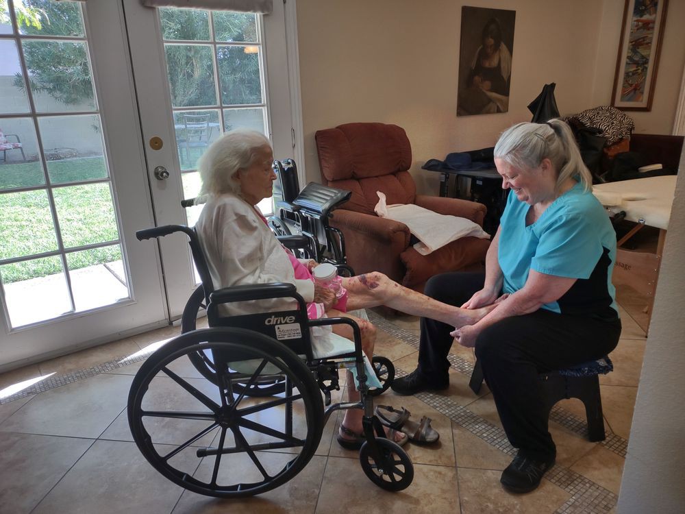 An elderly woman in a wheelchair interacting with a caregiver indoors.