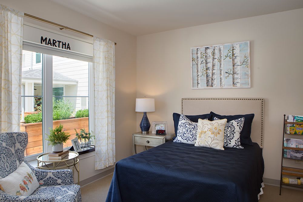 A modern and cozy bedroom with a navy blue bedspread, decorative pillows, and a bedside lamp.