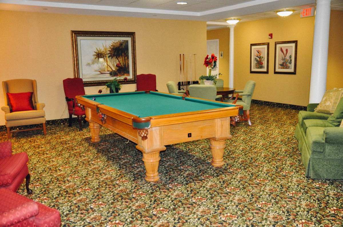 A cozy recreation room featuring a pool table, vibrant carpet, and elegant seating arrangements.