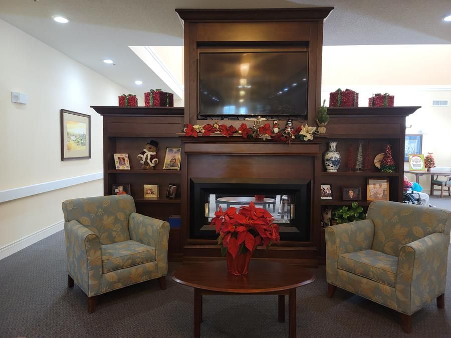 A cozy living room setup with a fireplace, two armchairs, and decorative elements.