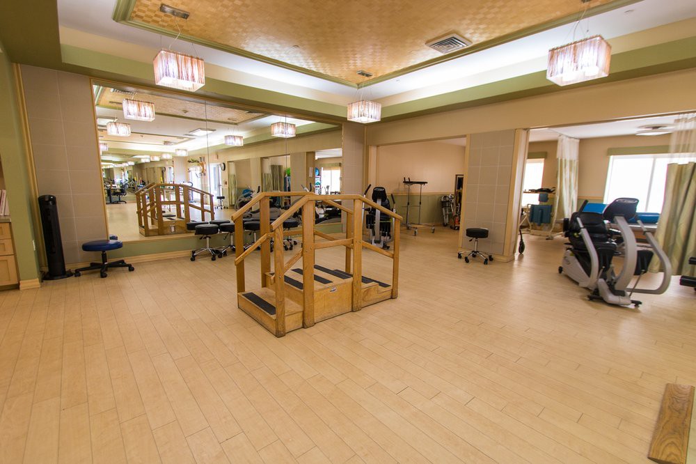 A spacious rehabilitation therapy room with various exercise equipment.