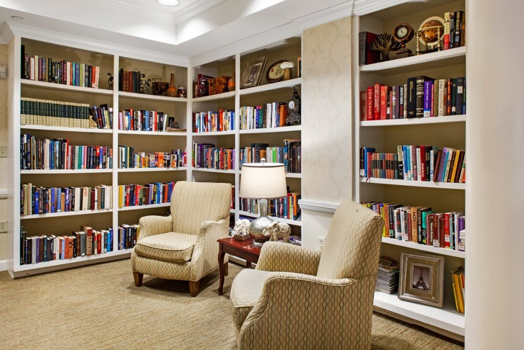 A cozy reading nook with armchairs and bookshelves filled with books.