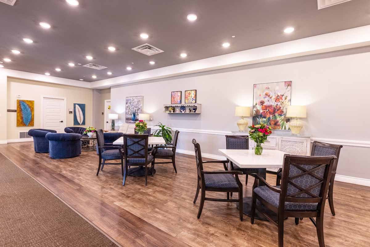 A cozy lounge area with tables and chairs, decorated with flowers and artwork.