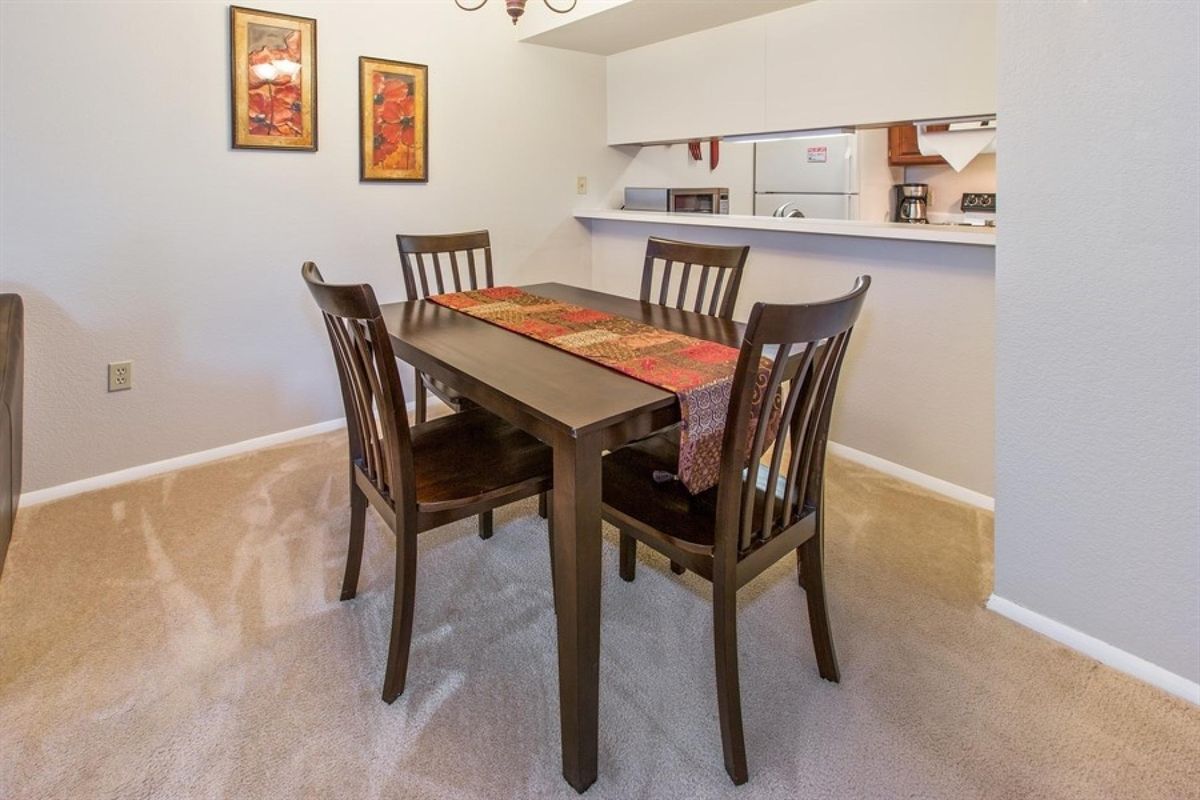 A cozy dining room with a wooden table and four matching chairs, decorated with a table runner.