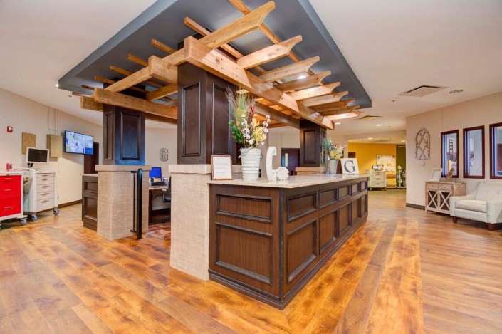 A modern hotel lobby with a wooden reception desk and open ceiling design.