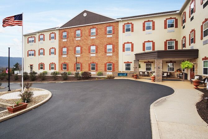 A multi-story hotel with a brick facade and a covered entrance accompanied by a roundabout driveway.