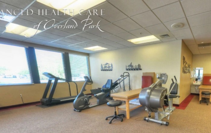 A well-equipped fitness room featuring exercise machines and a physiotherapy table.