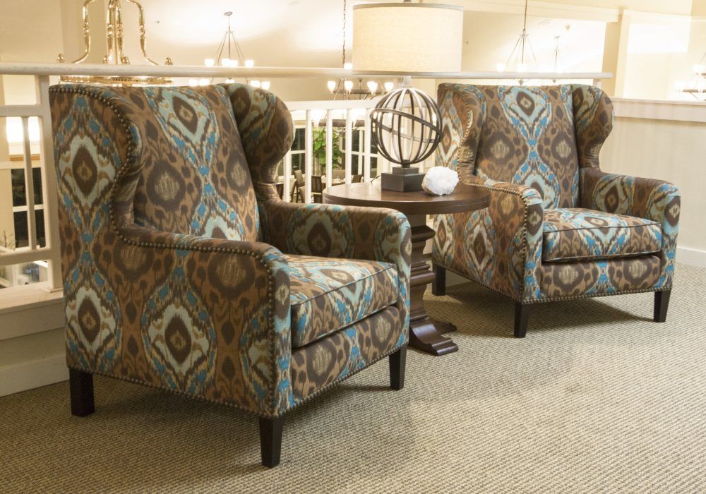 A cozy sitting area featuring two patterned armchairs and a small round table with decorative items.