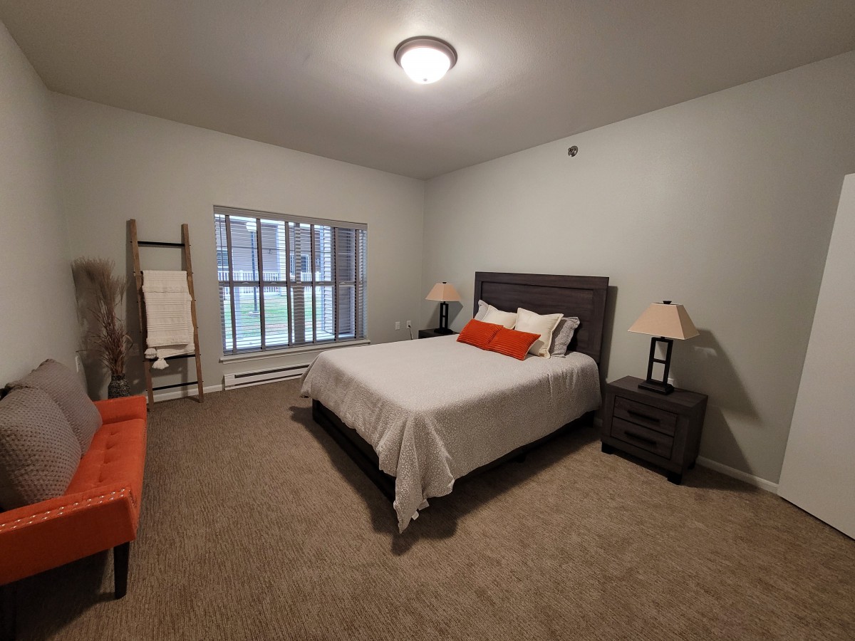 A neatly arranged bedroom with a bed, nightstands, and a window providing natural light.