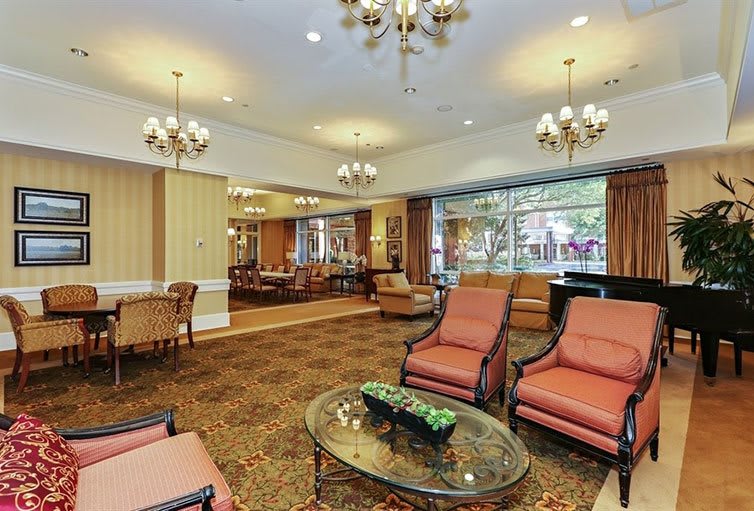 A spacious and elegantly decorated lobby with comfortable seating, chandeliers, and large windows.