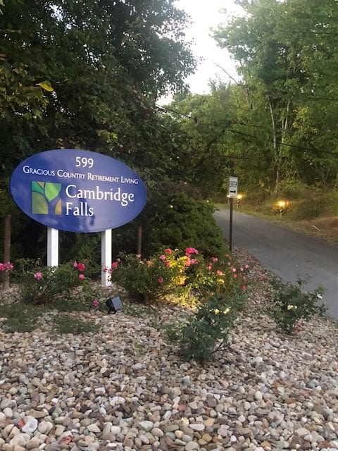 Entrance sign to Cambridge Falls with a landscaped pathway and flowers.