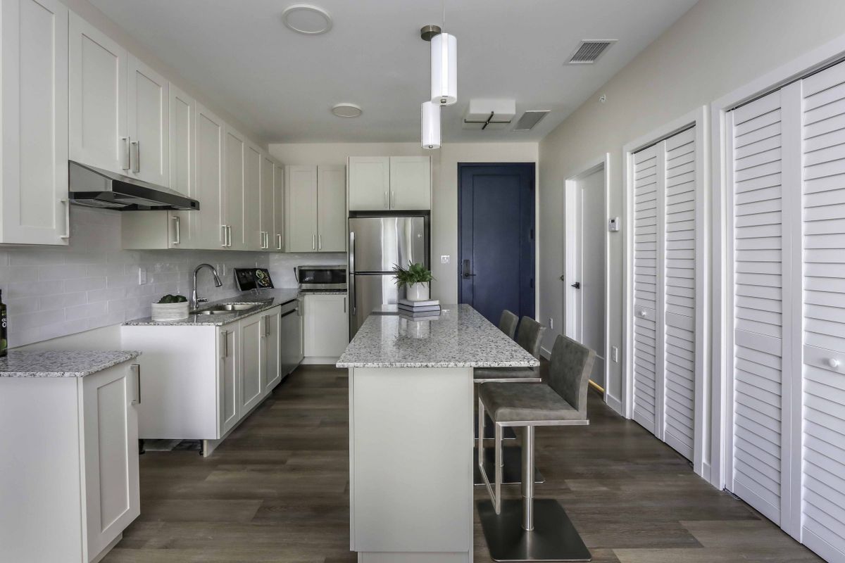 A modern kitchen with white cabinets, stainless steel appliances, and a central island with pendant lighting.