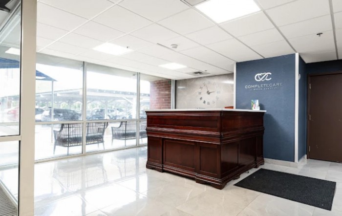 Modern office reception area with a wooden desk and seating.