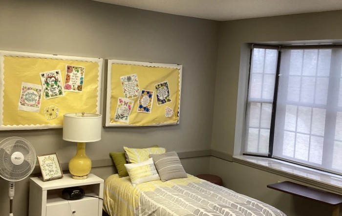 A cozy bedroom with yellow-themed decor and artwork above the bed.